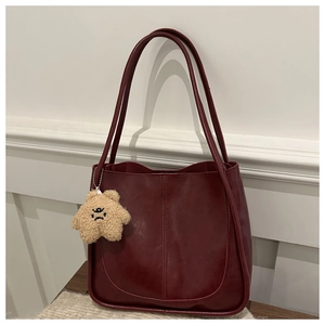 Detail of burgundy large tote bag featuring a cute star plush charm on soft leather