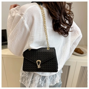 Detailed back view of woven black crossbody bag with gold hardware on a model