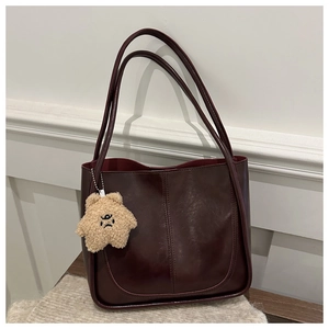 Detail of burgundy leather tote bag with vintage stitching and star plush pendant charm