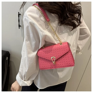 Detail of rose pink woven shoulder bag with gold chain strap shown on a model