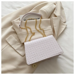 Close-up of pink woven texture on a square shoulder bag with gold chain strap detail