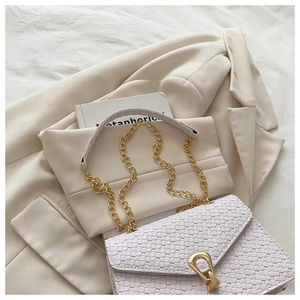 Detail of woven texture flap bag with elegant gold droplet buckle and chain strap