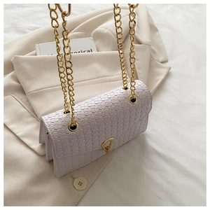 Detail of lavender woven crossbody bag featuring a golden triangular clasp and chain strap