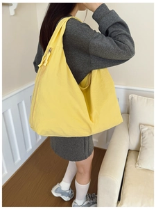 Spacious lemon yellow canvas tote bag worn by a model in a minimalist home setting