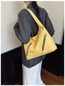 Detail view of yellow litchi pattern leather tote bag with decorative zippers