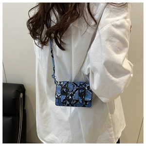 Détail du mini sac bandoulière bleu à motif serpent avec double boucle sur le mannequin