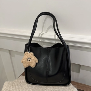 Minimalist black faux leather tote bag with long handles and a cute plush star charm