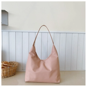 Detail view of pink hobo shoulder bag with litchi grain texture in a cozy home setting