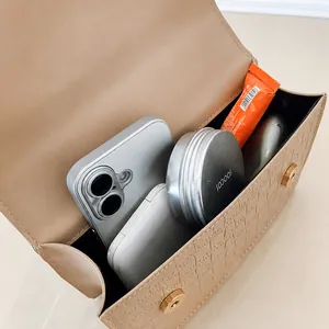 Vista detallada del interior del bolso de piel caqui con móvil y cosméticos