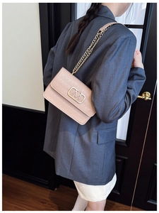 Detalle de bolso beige efecto cocodrilo con logo M dorado y correa de cadena