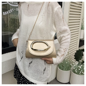 Detail of champagne gold evening clutch featuring a large metallic buckle on textured leather