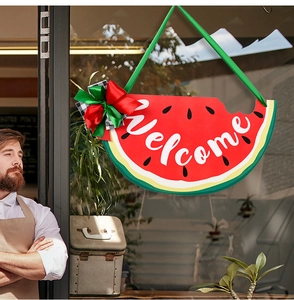 Detail of wooden watermelon welcome sign with bow hanging on a glass door