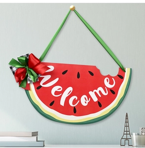 Watermelon wooden welcome sign with colorful bow hanging on a grey textured wall