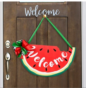 Detail of wooden watermelon welcome sign with bow and ribbon on a dark brown door