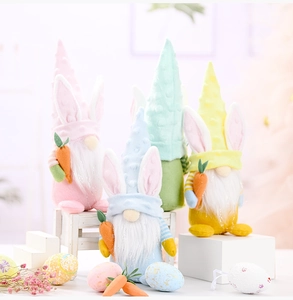 Close-up of Easter gnomes with rabbit ears holding carrots on a white decorative bench