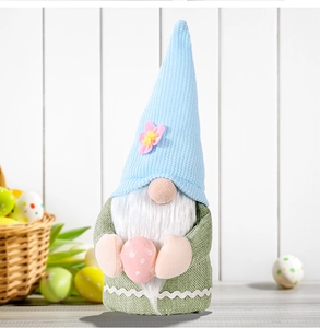 Detail view of a knitted Easter gnome plush holding a pink egg on a wooden surface