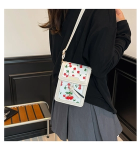 White crossbody phone bag featuring red cherry prints and a golden decorative buckle