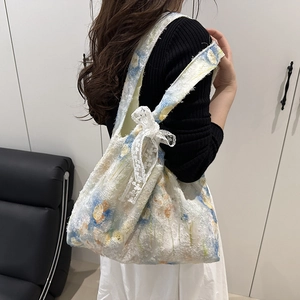 Detailed close-up of floral chiffon bucket bag with a delicate lace bow on the strap