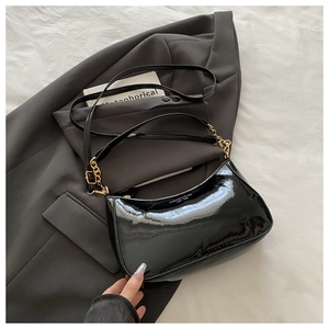 Détail du sac demi-lune en cuir verni noir avec chaîne dorée et texte de mode