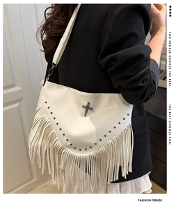 Détail d'un sac bandoulière blanc à franges avec rivets noirs et croix gothique