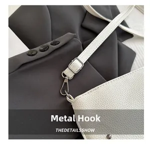 Détail du crochet en métal noir argenté et bandoulière de sac en cuir grainé blanc