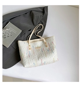 Macro detail of geometric embossed texture and multicolored wave embroidery on tote bag