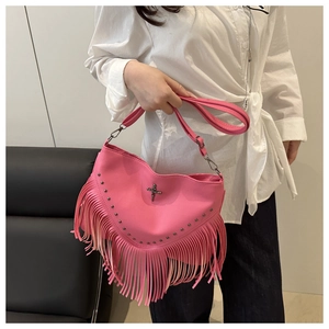Détail du sac à bandoulière rose en similicuir avec longues franges et pendentif croix