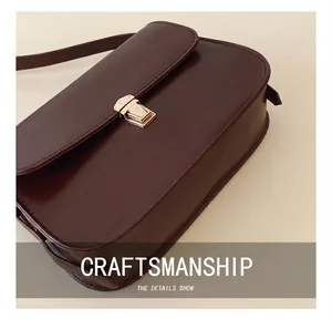 Close-up of vintage dark brown glossy leather bag with elegant gold metal buckle