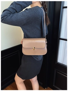 Detail view of a vintage light brown leather shoulder bag with a gold rectangular lock