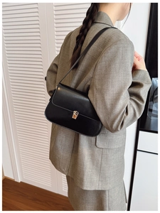 Sleek black faux leather baguette bag with silver metallic clasp worn with grey blazer