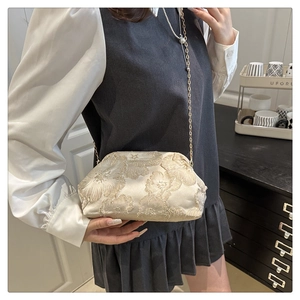 Detail of elegant beige jacquard evening bag with floral embroidery and chain strap