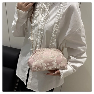 Détail d'une pochette en satin rose avec broderie florale et chaîne dorée