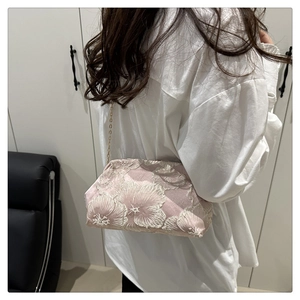 Detailed view of floral embroidery and gold chain strap on pink vintage makeup bag