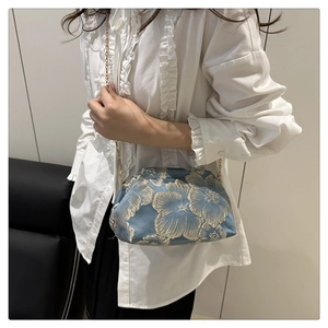 Détail d'un sac bandoulière en brocart bleu avec broderie florale et chaîne dorée