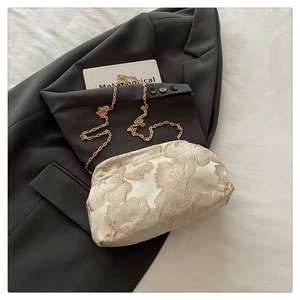 Gros plan sur la texture jacquard florale et la chaîne dorée du sac à main crème
