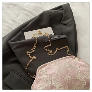 Détail du sac en satin rose avec broderie florale 3D blanche et bandoulière chaîne dorée