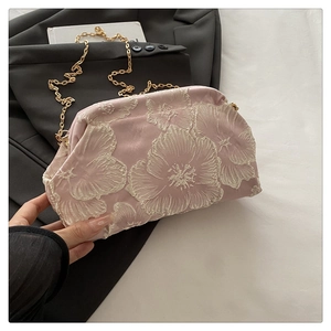Gros plan détaillé du sac en satin rose clair avec broderie florale blanche délicate