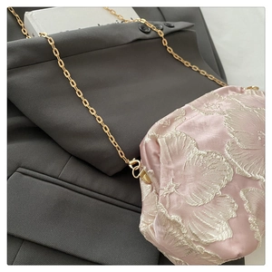 Détail du sac à main en soie jacquard rose avec motifs floraux et chaîne dorée