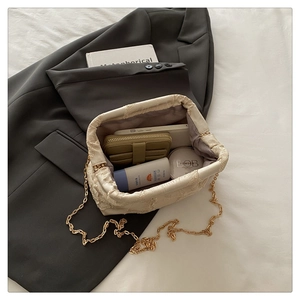 Vue de dessus du sac à chaîne crème montrant des objets du quotidien comme le mobile