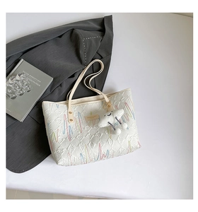 Detail of white quilted tote bag featuring colorful zigzag embroidery and cloud charm