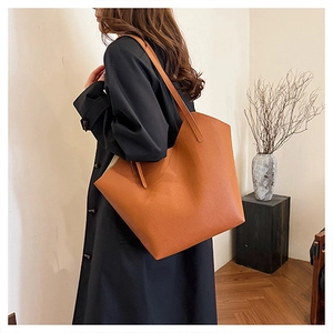 Detail of caramel tote bag showing premium lychee grain leather texture and wide shoulder strap