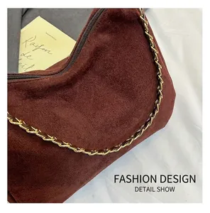 Detail of dark brown suede tote bag with golden chain strap and high-quality texture