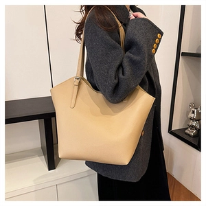 Detail of beige leather tote bag featuring refined lychee texture and adjustable shoulder strap