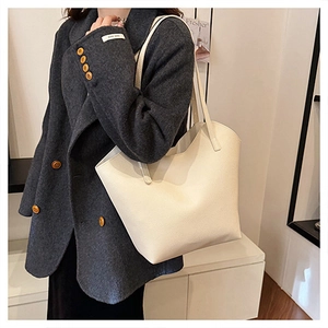 Close-up of cream white tote bag with litchi texture on a grey wool coat shoulder