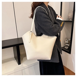 Detail of creamy white tote bag showing pebble leather texture and metal buckle on strap