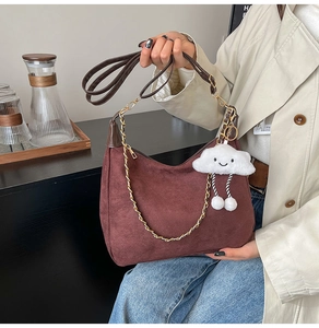 Close-up of burgundy suede hobo bag with gold chain and plush cloud charm