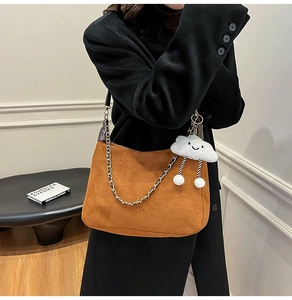 Brown suede tote bag with gold chain and plush cloud charm on a black coat model
