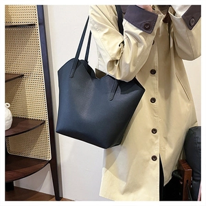 Lifestyle shot of large black pebble leather tote bag worn with a stylish trench coat