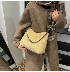 Detail of beige suede tote bag with chain strap styled with winter coat and scarf