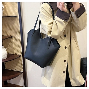 Detailed view of black large capacity tote bag with wave-edge design on model shoulder